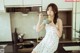 A woman sitting on a kitchen counter eating a bowl of noodles.