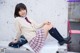 A young woman sitting on a bench wearing a school uniform.