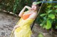 A woman in a yellow dress sitting on a swing.