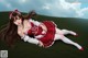 A woman in a red and white dress laying on the grass.