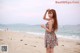 A woman in a floral dress standing on a beach.