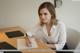 A woman sitting at a desk writing on a piece of paper.