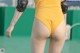 A woman in a yellow bodysuit with knee pads on her butt.