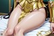 A woman in a gold outfit is sitting on a bed.