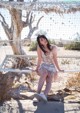 A woman sitting on a bench in the desert.