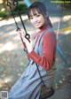 A woman sitting on a swing in a park.