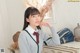 A woman in a school uniform sitting at a dresser.