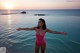 A woman in a pink bathing suit standing in the ocean.