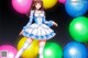 A girl in a blue dress standing in front of a bunch of balloons.